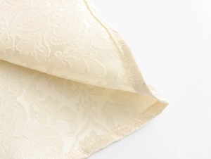 Vue macro du tissu jacquard crème montrant la texture tissée et les détails de la bordure