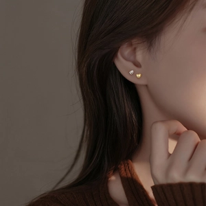 Elegant S999 sterling silver heart stud earrings shown in silver and gold on a female model