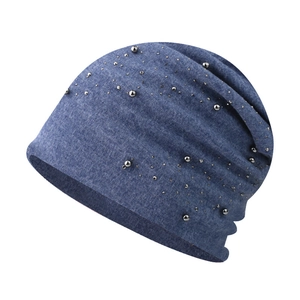 Detail of blue slouchy knit beanie with decorative pearls and rhinestones on white background
