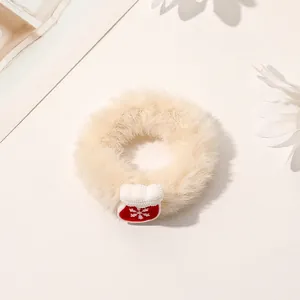 Detailed view of plush cream scrunchie with festive red snowflake Christmas sock ornament