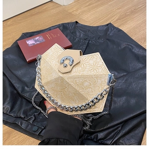 Detail view of cream geometric handbag featuring intricate lace texture and chunky metal chain