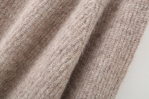 Macro shot of high-quality alpaca wool knit fabric showing warm oatmeal color and soft texture