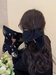 Detail of a large black jacquard scrunchie with gold floral embroidery on model hair
