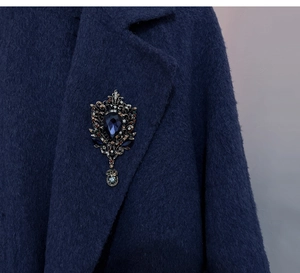 Detailed view of vintage water drop brooch with blue gemstone on wool coat lapel