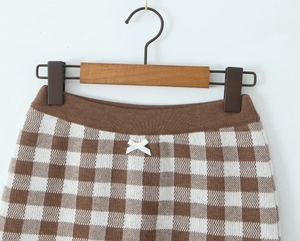 Detailed view of checkered knit shorts featuring a brown waist and white ribbon bow detail