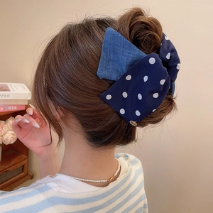 Close-up of a double-layered polka dot fabric bow hair tie with small gold metal charms