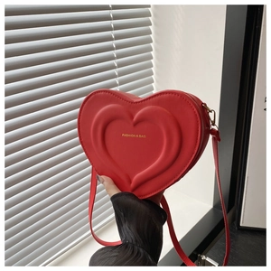 Close-up of red heart-shaped PU leather crossbody bag with FASHION & BAG text engraving