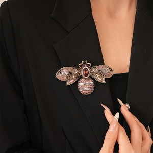 Detailed close-up of a vintage gold bee brooch with colorful crystals on a black blazer