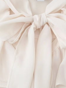 Detail of elegant cream chiffon blouse featuring a wide pussy-bow necktie and soft texture