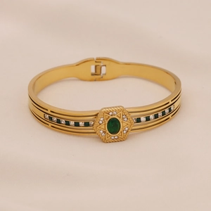 Détail d'un bracelet doré rétro orné d'une pierre vert émeraude et de petits zircons