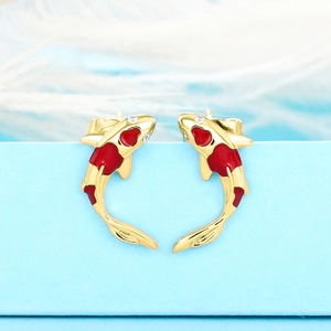 Macro view of gold-plated koi fish earrings with red enamel and sparkling zircon accents