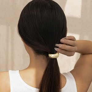 Close-up of golden geometric hair cuff on a ponytail with a glossy mirror finish