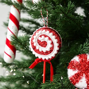 Red and white glitter Christmas candy cane ornament hanging on a green Christmas tree