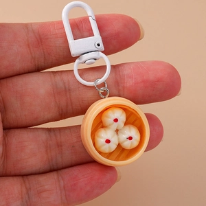 Detailed close-up of a creative miniature dumpling steamer keychain with orange resin basket