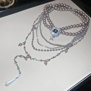 Detailed macro view of a multi-layer purple pearl necklace with blue gemstone and star pendant