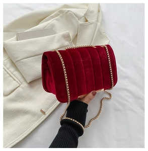 Macro shot of dark red velvet texture and golden chain on a trendy crossbody bag