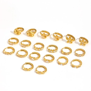 Flat lay of multiple gold hoop earrings with zircon stones on a white background