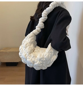 Detailed view of a white quilted cloud bag with fluffy shoulder strap worn by a model