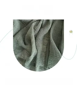 Detail of pea green linen scarf fabric showing breathable crinkle texture and soft fibers