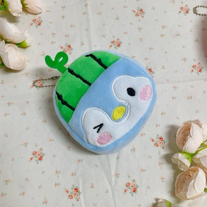 Close-up of plush penguin keychain with green watermelon hat on a floral fabric background