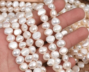 Close-up of white 9-10mm baroque freshwater pearls wrapped around fingers for jewelry DIY