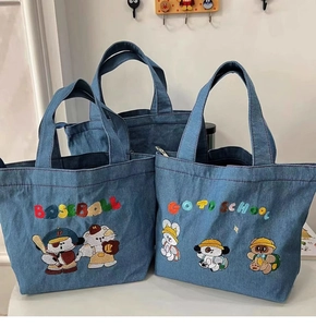 Detail of blue denim handbags featuring colorful baseball and school embroidery motifs