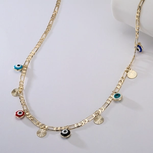 Macro shot of gold-plated Figaro chain necklace with colorful evil eye and sunburst charms