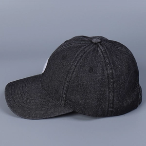 Close-up of washed black denim baseball cap showing six-panel stitching and twill texture