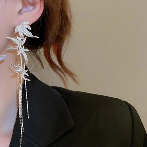 Detail view of silver bamboo leaf tassel earrings worn on model for a modern look