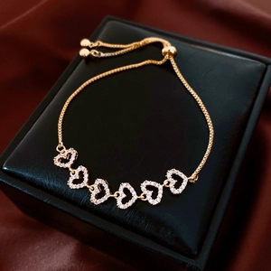 Detail view of gold-plated heart bracelet with zircon stones on a luxury velvet background
