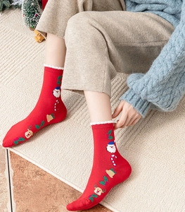 Close-up of red Christmas crew socks with Santa Claus patterns and white faux fur cuffs