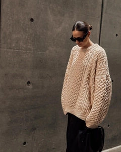 Détail d'un pull beige épais en maille torsadée avec col roulé et épaules tombantes