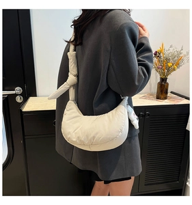 Sac hobo matelassé crème avec bandoulière nouée et pendentif lapin porté par un mannequin