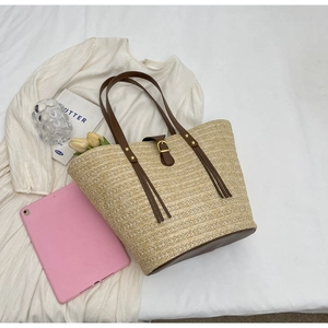 Flat lay of woven straw tote bag with brown leather straps and summer lifestyle items