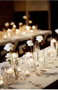 Detail van elegante drijfkaarsen en witte rozen in glazen cilindervazen voor bruiloften