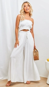 Detail of white two-piece strapless top and wide-leg trousers in breathable cotton linen