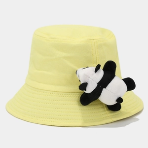 Close-up of yellow canvas bucket hat with cute panda plush toy and fabric texture