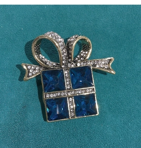 Macro shot of vintage gift box brooch with deep blue crystals and gold ribbon detail
