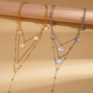 Detail of layered gold and silver coin necklaces with Capricorn engraving on round pillars