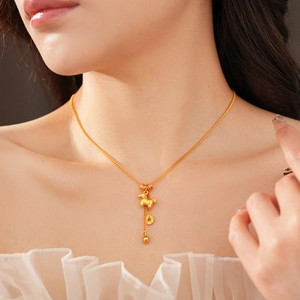 Detail of gold-plated necklace with horse and coin pendant worn on a female neck