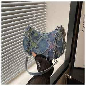Detail of blue denim shoulder bag with colorful stars and frayed edges featuring metal chain