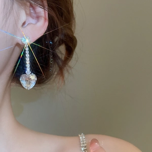 Close-up of sparkling heart-shaped zircon drop earring worn with elegant starburst effect