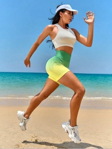 Dynamic beach shot of high-waisted green-yellow gradient yoga shorts and white sports bra
