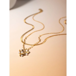 Macro detail of 18k gold heart pendant featuring inlaid pearls on a double layer chain