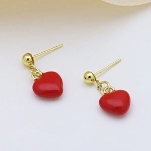 Detailed close-up of red enamel heart drop earrings with gold bead studs on white