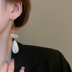 Détail de boucles d'oreilles pendantes en perle argentée avec fleurs en zircon
