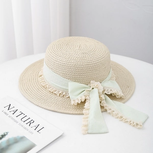 Detail of mint green polka dot ribbon and white lace on beige straw boater hat