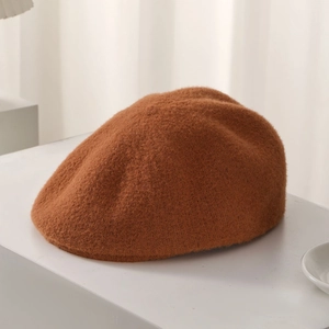 Detail of warm brown plush beret featuring thick knitted texture and soft woolly surface