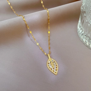Detailed view of a gold leaf-shaped pendant with cubic zirconia on a delicate chain