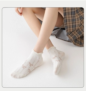 Close-up of white summer mesh socks with brown bows and frilly ruffled edges for women